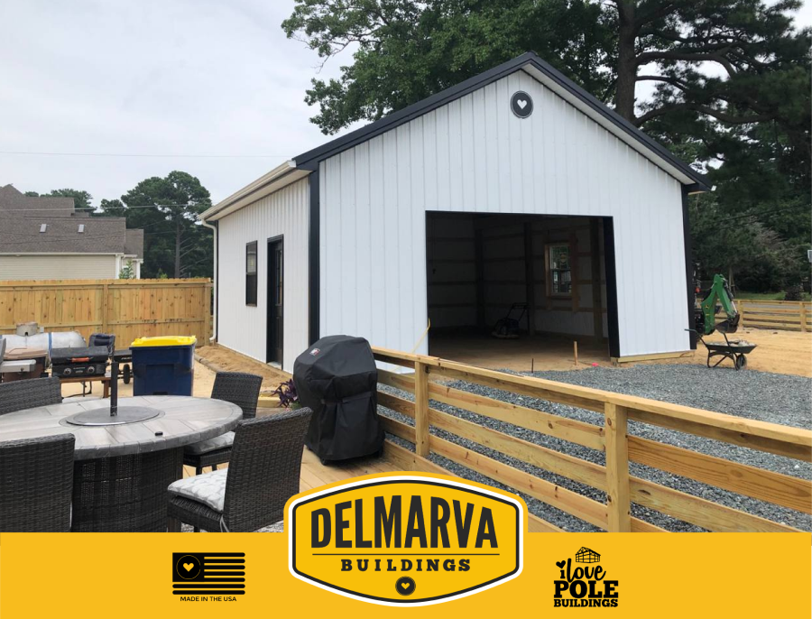 White pole barn garage by Delmarva Buildings with black trim and open bay door.