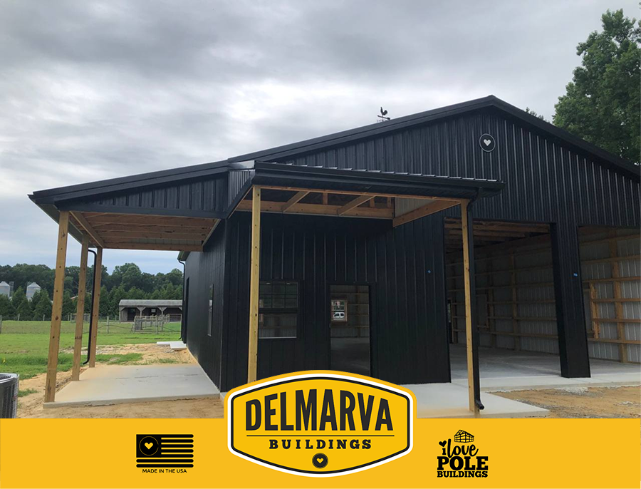 Black pole barn with wood-framed covered porches and large doors.