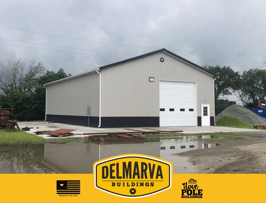 Gray and black pole barn with white garage door and side entry by Delmarva Buildings.