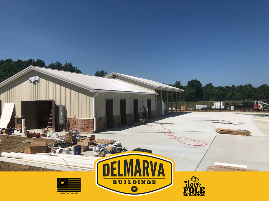 Tan and brick pole barn with metal roof and open bays under construction by Delmarva Buildings.