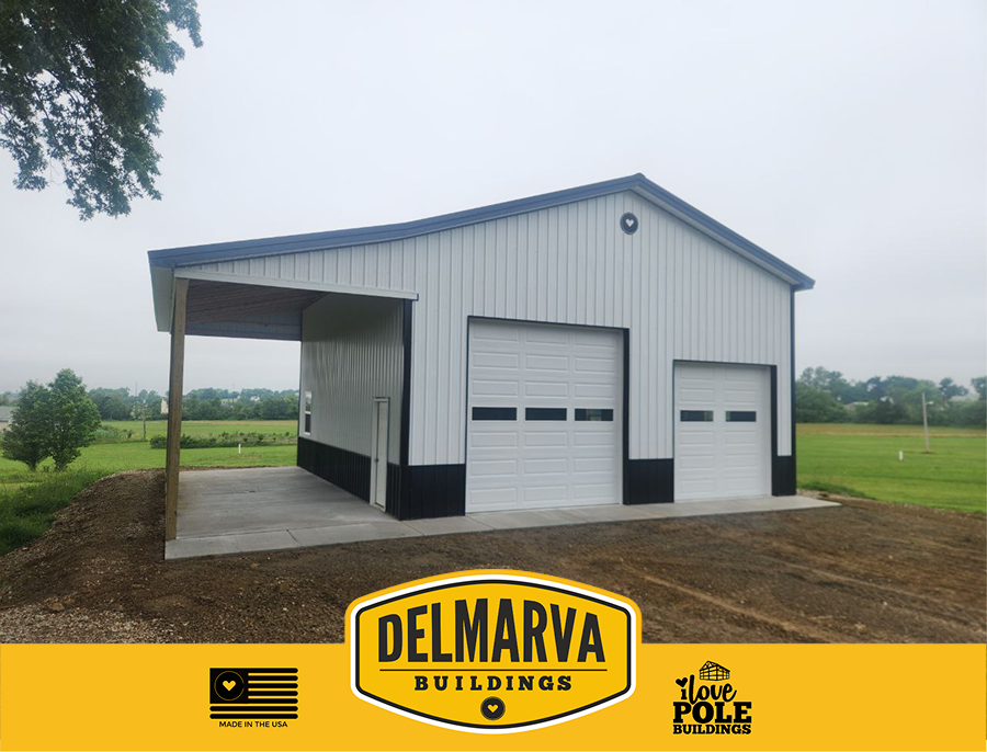 White and black pole barn with two white garage doors and covered lean-to by Delmarva Buildings.