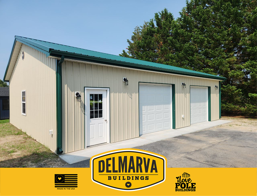 Cream pole barn with green roof and trim, two white garage doors, and entry door by Delmarva Buildings.