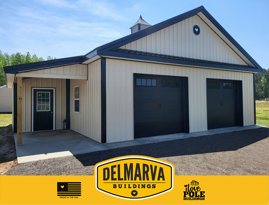 Cream and black pole barn with two black garage doors, cupola, and side entry by Delmarva Buildings.