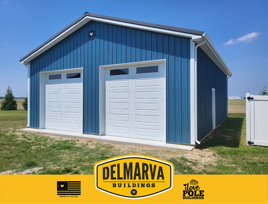 Blue pole barn with two white garage doors and white trim by Delmarva Buildings.