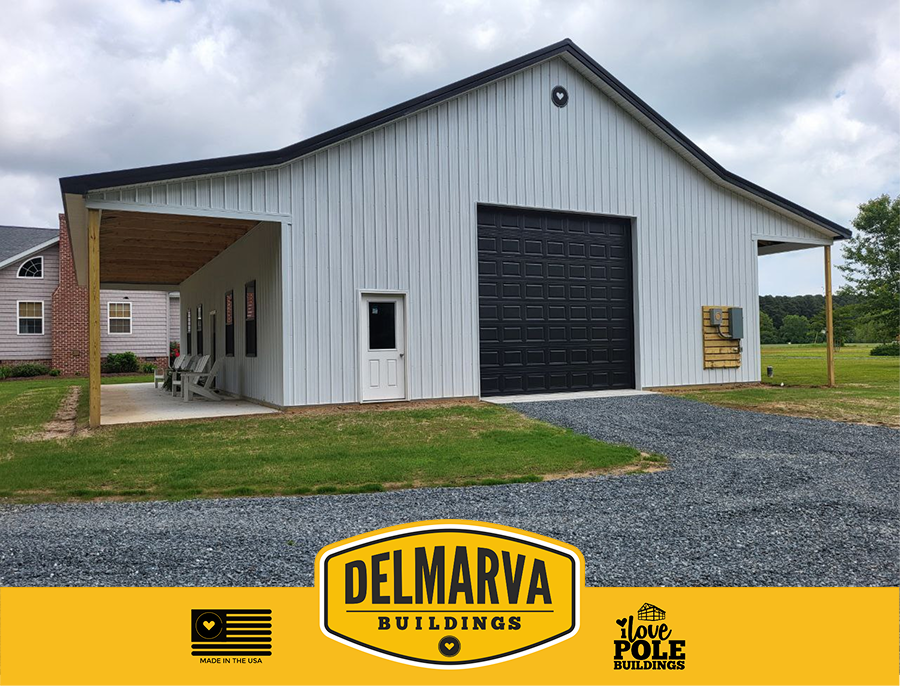 Gray pole barn with black garage door, covered porches, and wood trim by Delmarva Buildings.