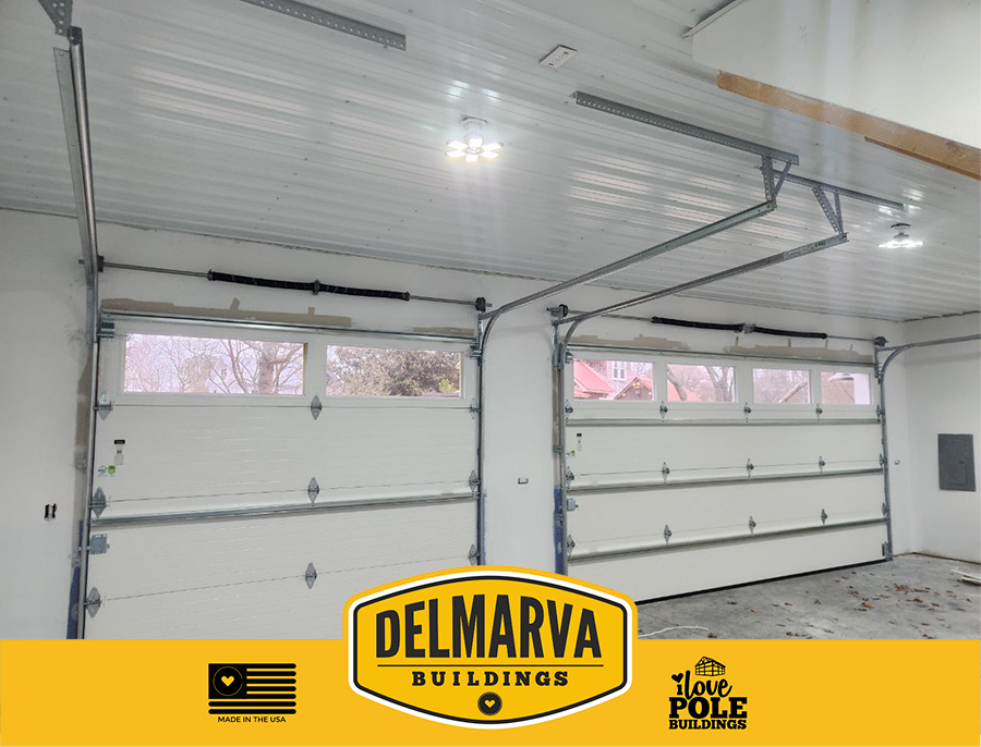 Interior of two-bay garage with white doors and metal frame by Delmarva Buildings.