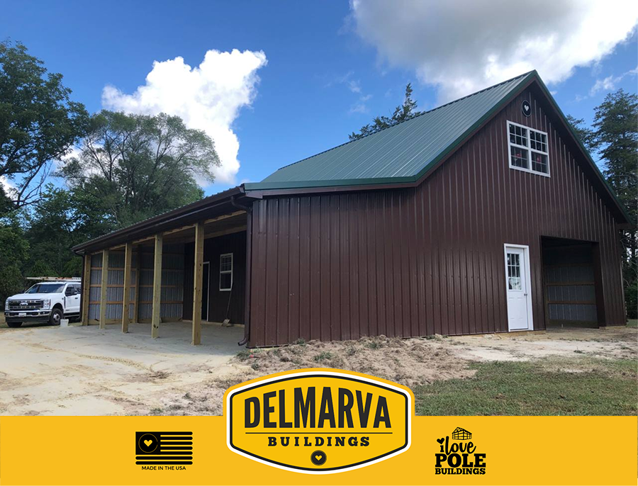 Brown pole barn with dark green roof, covered porch with an open garage.
