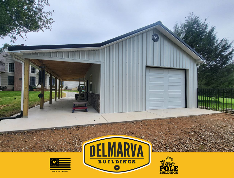 White pole barn with a dark green roof, front porch, and single garage door built by Delmarva Buildings.